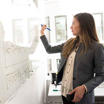 An image of a woman writing on a whiteboard