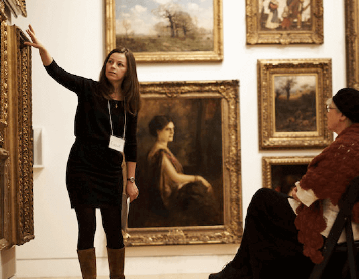a woman points at a painting in a museum