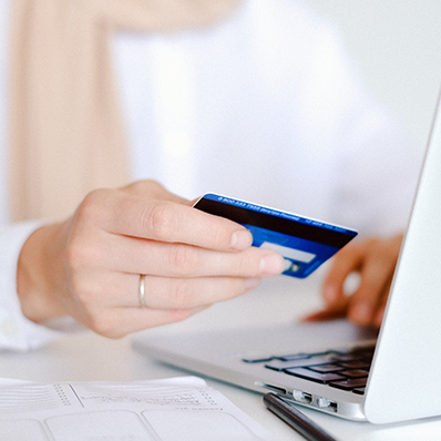 a woman types at a keyboard with a credit card