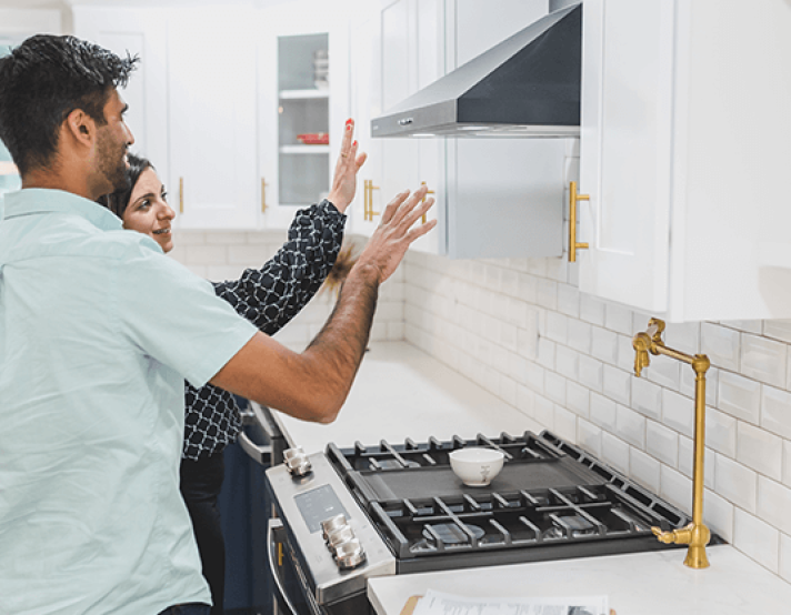 two people look over a stove